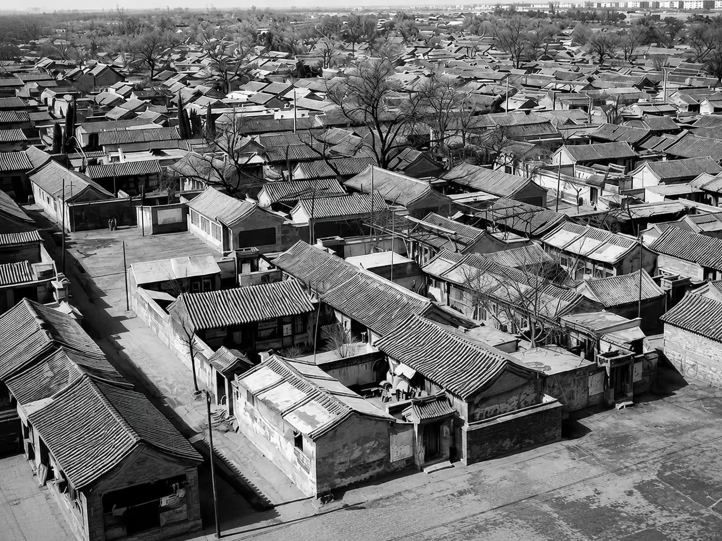 A Beijing siheyuan courtyard with grey bricks, tiled roofs, and a screen wall