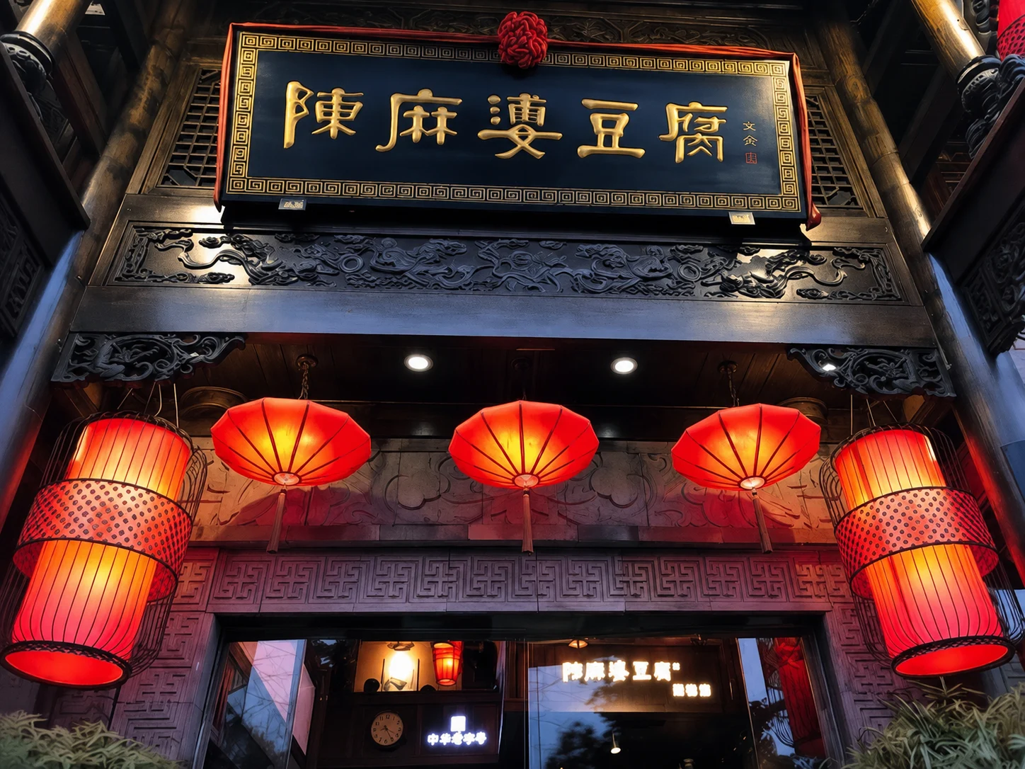 A framed portrait or statue of Chen Mapo, the woman credited with inventing mapo tofu, displayed in a restaurant