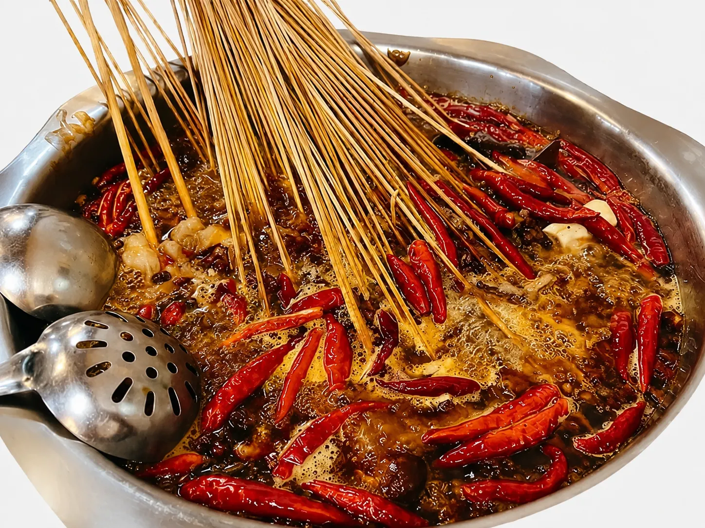 Colorful bamboo skewers of meat and vegetables arranged in a bubbling red hotpot