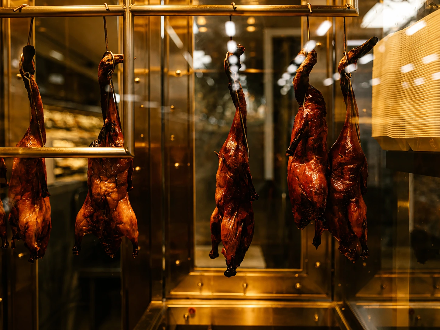Rows of glistening roast ducks and char siu pork hanging behind a glass window in a Cantonese roast meat shop
