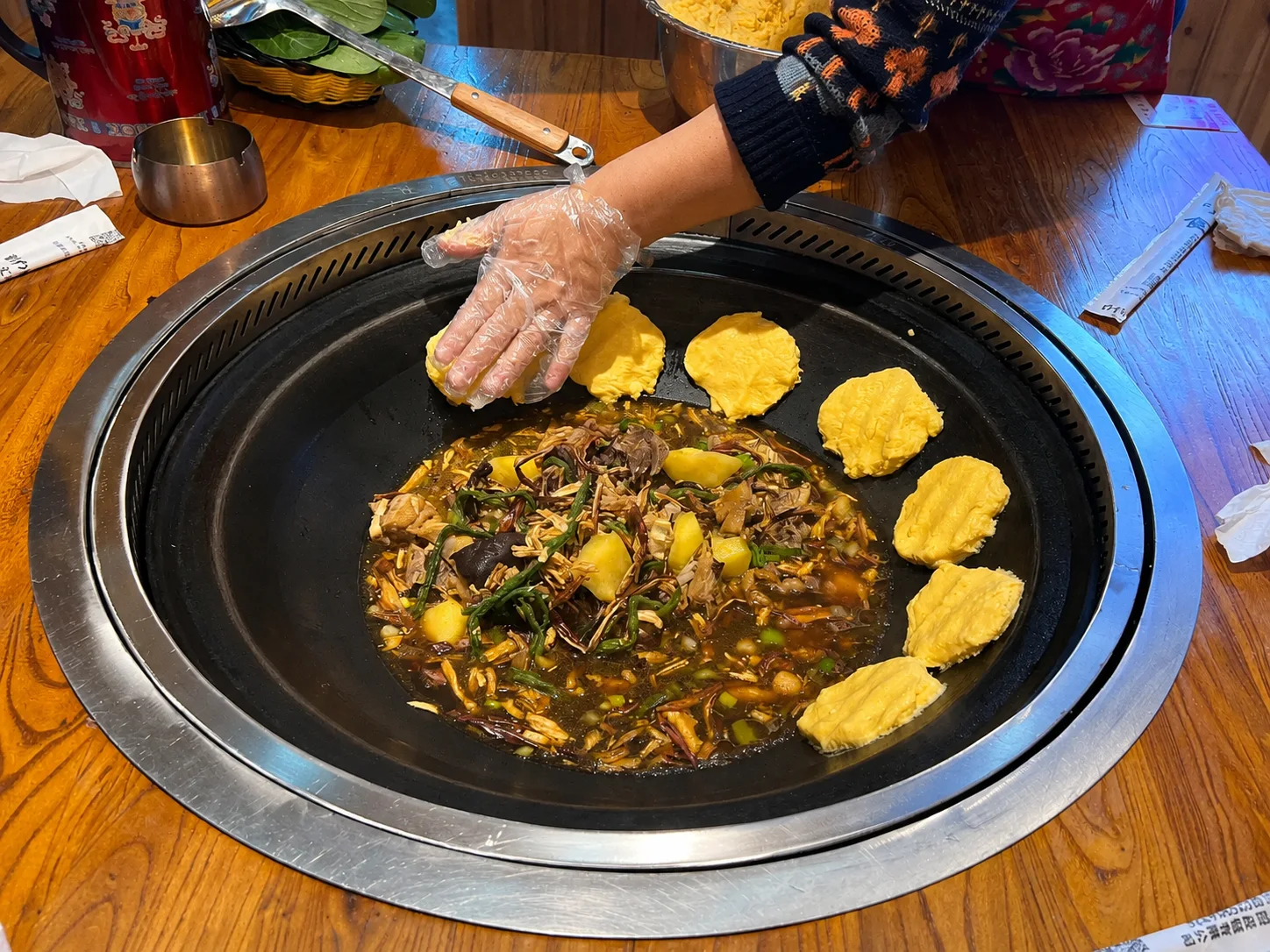 A steaming Northeast China iron pot stew filled with pork, potatoes, corn, cabbage, and noodles
