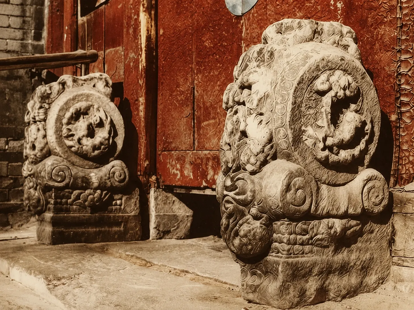 A pair of carved stone drum-shaped supports flanking the wooden gate of a siheyuan