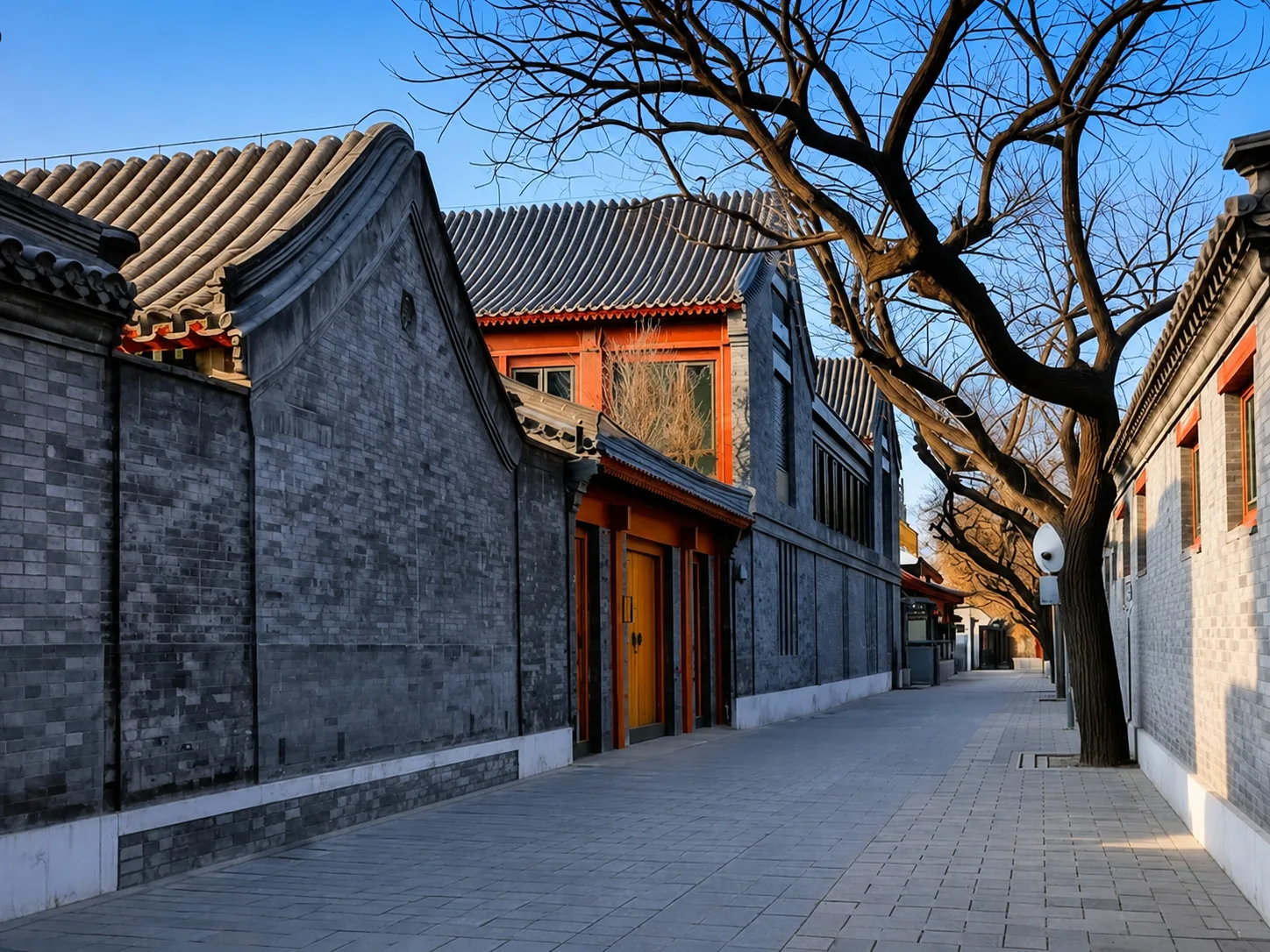 A narrow hutong lane running alongside the high grey walls of a siheyuan compound