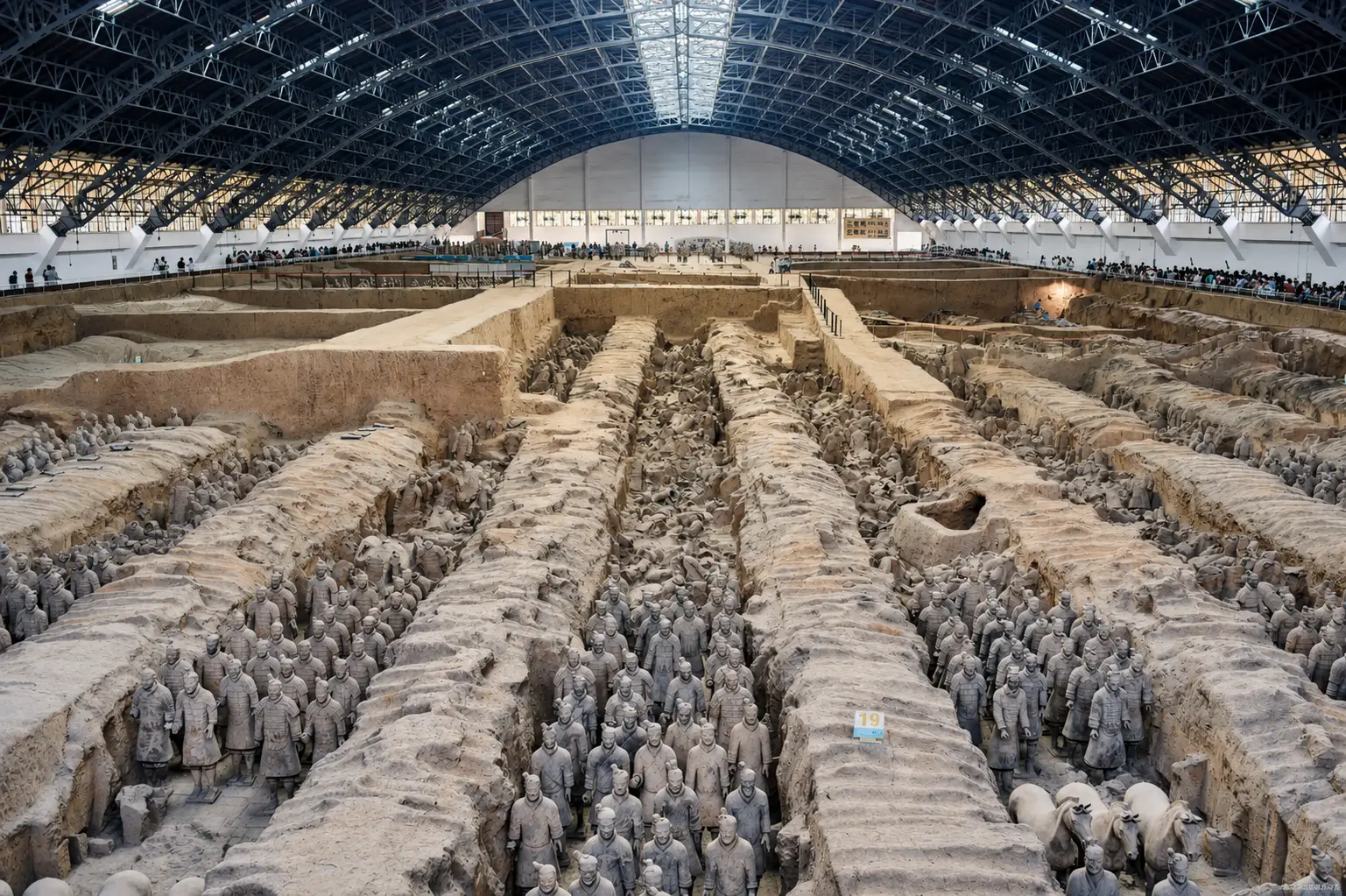 A vast archaeological pit filled with rows of terracotta warriors, only one of several excavation halls